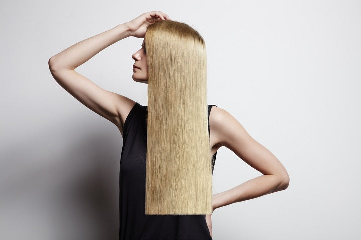 kobieta z długimi blond włosami prezentująca zastosowanie serum na końcówki