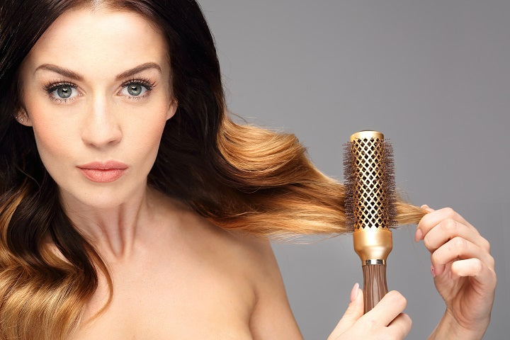 szczotka do modelowania włosów obok pięknej młodej kobiety, brunetki z blond refleksami